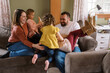 © Serena Burroughs/Stocksy - Smiling happy family playing with kids on couch in home