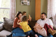 © Serena Burroughs/Stocksy - Smiling happy family playing with kids on couch in home