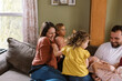 © Serena Burroughs/Stocksy - Smiling happy family playing with kids on couch in home