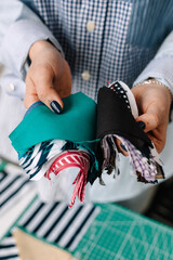 Crop woman seamstress showing pieces of various fabric 