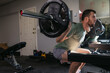 © Rob and Julia Campbell/Stocksy - Man performing squat exercises in home gym.