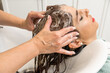 © Alvaro Lavin/Stocksy - woman hairdresser washing long hair with soap in hairdresser's shop