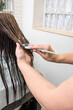 © Alvaro Lavin/Stocksy - woman hairdresser giving hair treatment to woman with long brown hair