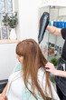 © Alvaro Lavin/Stocksy - woman hairdresser drying long wet hair in hairdresser's salon