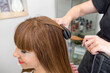 © Alvaro Lavin/Stocksy - woman hairdresser ironing and styling client's hair