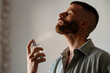 © Lucas Ottone/Stocksy - Man applying perfume to his neck