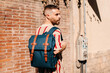 © Lucas Ottone/Stocksy - Urban man walking with a backpack