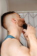 © Lucas Ottone/Stocksy - Man at home trimming his beard