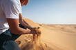 © Pedro Merino/Stocksy - Man picking up desert sand between his hands