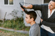 © ByLorena/Stocksy - Woman shaving her teenage son's hair outdoors