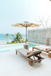 © Marc Tran/Stocksy - Fantastic overwater villa with sun beds chairs under umbrella,