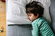 © Maria Manco/Stocksy - Ovehrhead view of boy on couch at home while sick with cold and flu