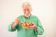 Smiling senior bearded man holding bowl of fresh seasonal fruit ready to eat. Breakfast or lunch, eat healthy and dietary