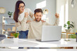 © Studio Romantic - Family couple gets excited about accepted application, cool job offer and career success. Young man and woman smiling, doing fist gestures and looking at laptop computer with happy face expressions