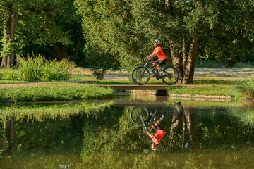 Wall Mural - attractive senior woman cycling with her electric mountain bike in the city park of Stuttgart, Baden-Wuerttemberg, Germany