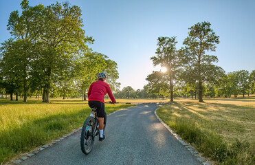 Wall Mural - attractive senior woman cycling with her electric mountain bike in the city park of Stuttgart, Baden-Wuerttemberg, Germany