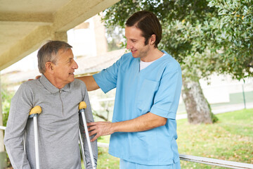 Wall Mural - Nurse supporting senior man with disability in garden