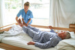 © Robert Kneschke - Nurse lifting legs of senior man lying in bed