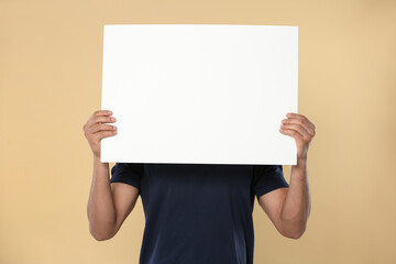 Wall Mural - man holding sheet of paper on beige background, closeup. mockup for design