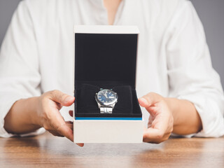 Hands holding a gift box with a luxury wristwatch for Father's Day, Valentine's Day, Mother's Day, and more