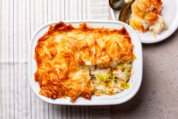 Canvas Print - Top view of chicken and leek filo pastry pot pie. Homemade food. Light beige table background.