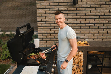 A man on the street is cooking a steak on the grill at a barbecue