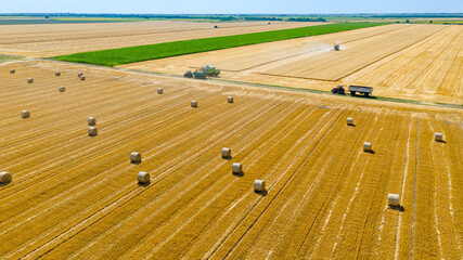 Aerial view over agricultural fields in harvest time, season, round bales of straw over harvested field