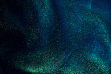 Wall Mural - gold dust particles creating shiny waves in a blue liquid with a green tint. glittering golden parti