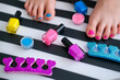Children's feet with bright pedicure and manicure of different colors and bottles of bright nail polish. Little girl does a pedicure. Beauty salon game. Children's entertainment.