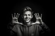 © Markus Schröder - Lifestyle portrait photography of a joyful boy in his 20s forming a circle with the fingers to say perfect against a dark grey background. With generative AI technology