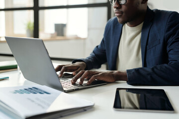 Aufkleber - Hands of young African American businessman in formalwear sitting in front of laptop and typing while sitting by workplace in office