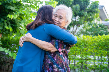 Asian elderly woman hug with her daughter with love, care, help, encourage and empathy at park, healthy strong medical concept.