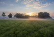© Space Creator - Idyllic meadow with trees and misty fog under dramatic sunrise sky. Czech landscape