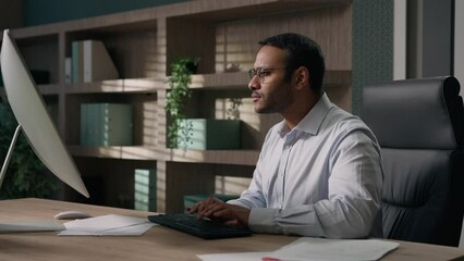 Indian man in glasses Arabian businessman American worker employer typing chatting working in office computer corporate software business project coder programming touch eyeglasses busy at workplace