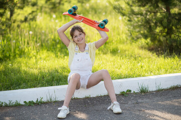 a little girl holds a penny board outdoors. the concept of transportation. sports on wheels. traveli
