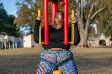 Wall Mural - Young fat woman doing barre exercise chest and shoulders in the park by the lake. Healthy lifestyle