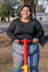 Wall Mural - Young fat woman doing leg exercise in the park by the lake. Healthy lifestyle