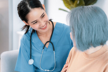 Wall Mural - A caregiver rest her hands on the shoulders of a contented senior patient while she sitting on the sofa at home.