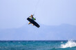 © PJenz - Kitesurfing girl jumping high in turquoise waters with mountains in the background