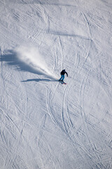 Skiing down mountain slope with white snow powder projecting from behind skier wearing black and blue outfit,  Les Deux Alpes, Isère, Auvergne-Rhône-Alpes, France, 2/3