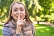 © Asier - Middle-aged woman in a park on a sunny day shouting and holding palm near opened mouth.