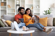 © Prostock-studio - Happy Young Indian Couple Relaxing At Home With Smartphone And Digital Tablet