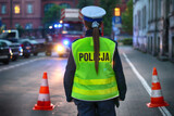 Fototapeta  - Policjantka polska w kamizelce odblaskowej wieczorem pilnuje ruchu w mieście.