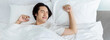 © paulaphoto - Portrait of handsome young asian man with enjoy fresh soft bedding linen mattress in white bed room modern retro apartment. Asian guy sleep stretch resting, good night sleep concept panoramic banner