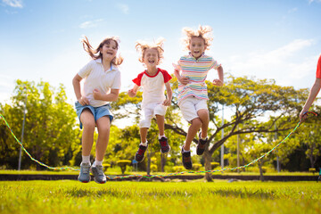 Happy kids play outdoor. Children skipping rope.