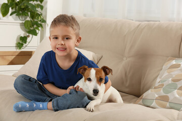 Sticker - Little boy with his cute dog on sofa at home, space for text. Adorable pet