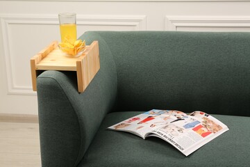 Poster - Glass of juice, chips and magazine on sofa with wooden armrest table in room. Interior element