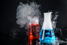 Laboratory Glassware With Colorful Liquids And Steam On Black Background. Chemical Reaction
