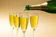 Close-up of champagne pouring in champagne flutes against beige background, copy space