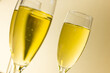 Close-up of champagne in champagne flutes against beige background, copy space
